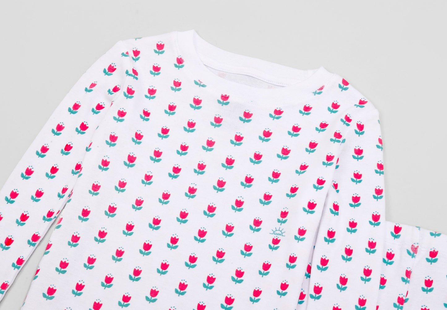 View of Pajama Set - Close up of tulips print (bright pink tulips with turquoise leaves and GMM logos).
Pajamas are white fabric with a vibrant tulips print. Pajamas are long-sleeved and made from GOTS certified, 100% organic cotton.
good morning monsters pajamas, loungewear, sleepwear, pajamas, boys, girls, baby, unisex