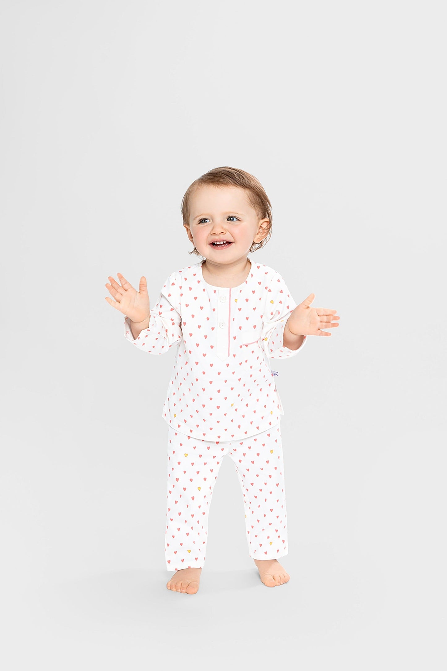 model wearing hearts print pajamas (solid white fabric with pink hearts); good morning monsters woven pajamas, loungewear, sleepwear, loose-fitting pajamas, boys, girls, baby, unisex