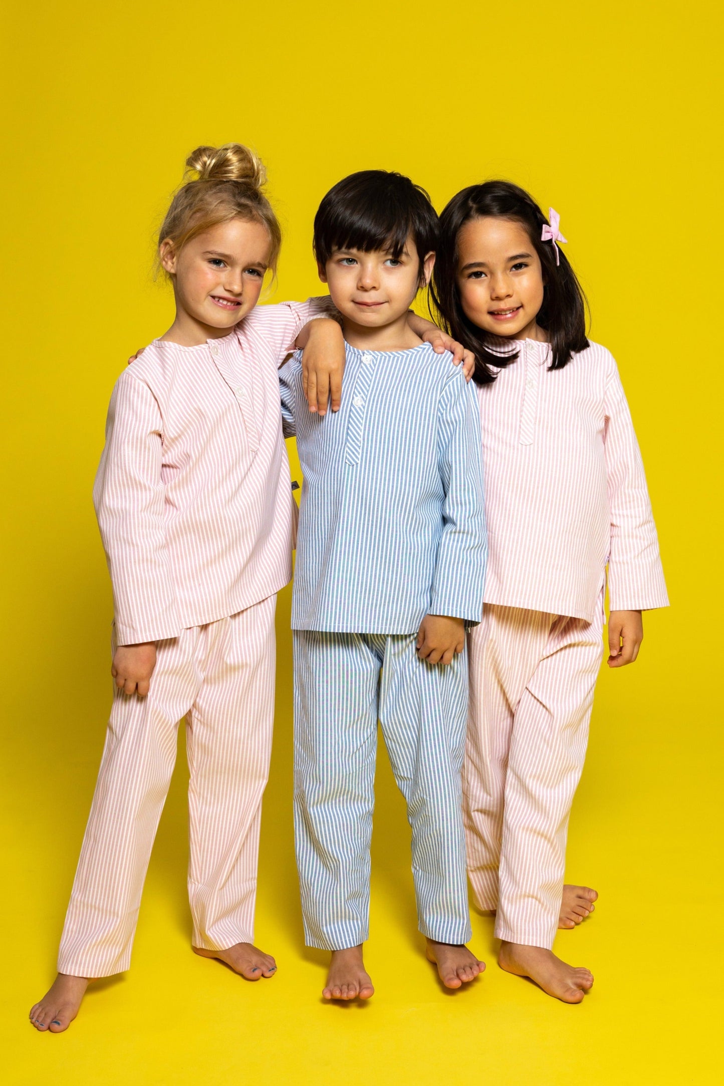three models wearing good morning monsters pinstripe pajamas (two models are wearing pink pinstripes, the center model is wearing blue pinstripes), good morning monsters woven pajamas, loungewear, sleepwear, loose-fitting pajamas, boys, girls, baby, unisex