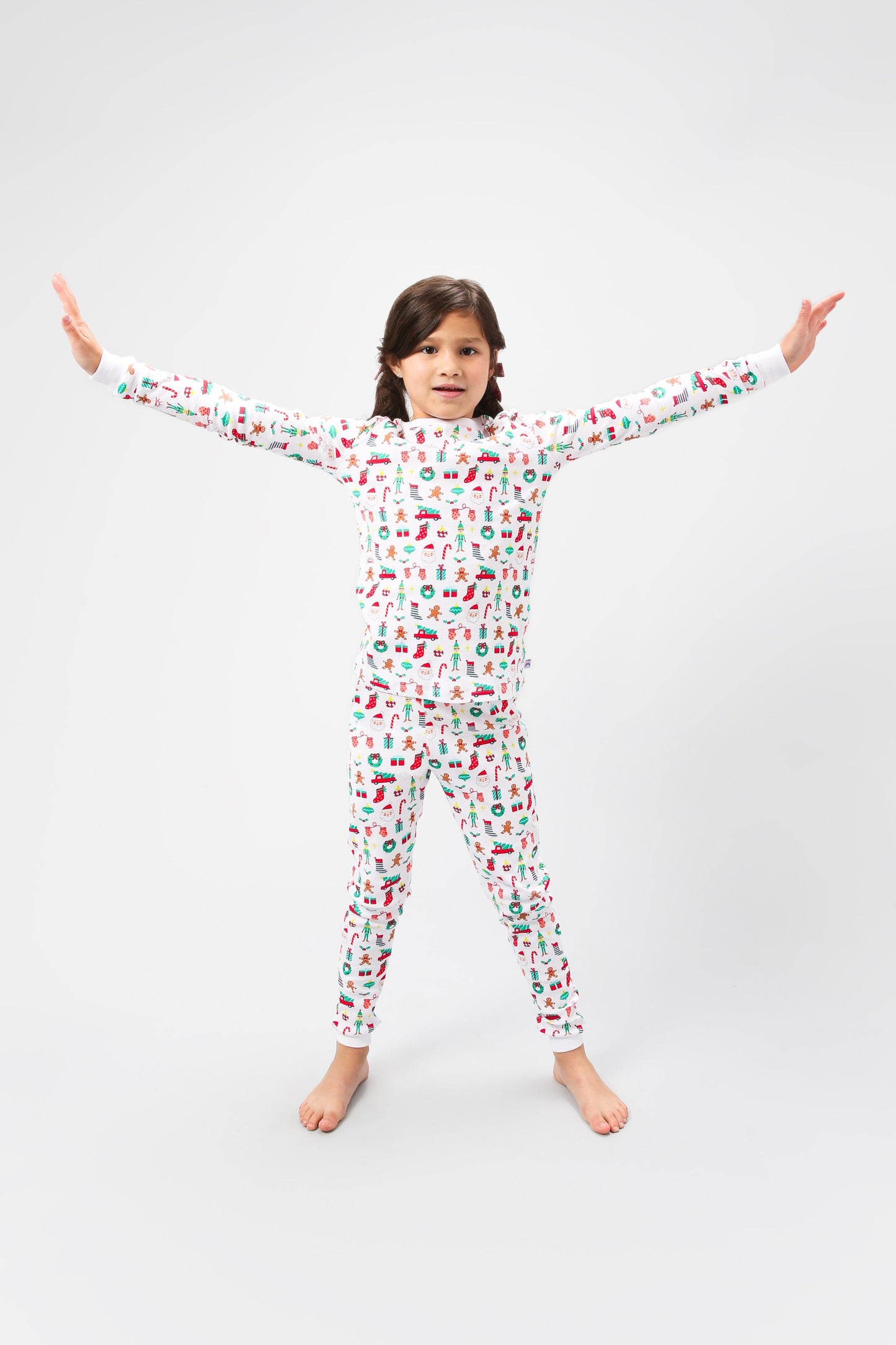 Front view of model arms out posing, wearing Christmas, festive, Santa, Elves, Classic Christmas, Holiday, Ornaments, Stockings, Gingerbread, Red Trucks pajama set.
Pajamas are white, lightweight fabric with a vibrant Christmas print. Pajamas are long-sleeved and made from GOTS certified, 100% organic cotton.
good morning monsters pajamas, loungewear, sleepwear, pajamas, boys, girls, baby, unisex