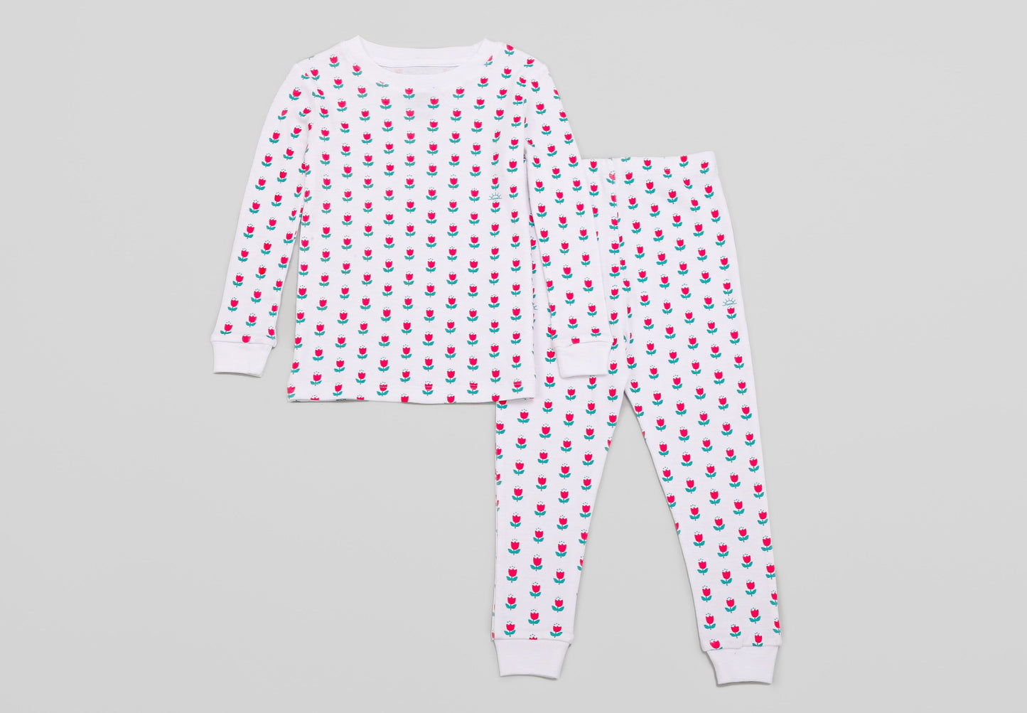 View of Pajama Set - Top & Bottom.
Pajamas are white fabric with a vibrant, tulips print (bright pink tulips with turquoise leaves). Pajamas are long-sleeved and made from GOTS certified, 100% organic cotton.