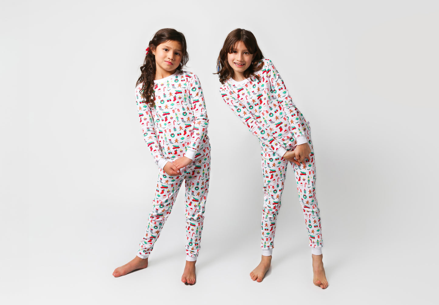 Front view of models posing, wearing Christmas, festive, Santa, Elves, Classic Christmas, Holiday, Ornaments, Stockings, Gingerbread, Red Trucks pajama set.  
Pajamas are white, lightweight fabric with a vibrant Christmas print.   Pajamas are long-sleeved and made from GOTS certified, 100% organic cotton.
good morning monsters pajamas, loungewear, sleepwear, pajamas, boys, girls, baby, unisex