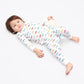 Toddler in long-sleeved, 100% GOTS certified organic cotton pajamas. 
 Pajamas are white, lightweight fabric with a vibrant, colorful, vehicles print with cars, jeeps, trucks, and buses.
good morning monsters pajamas, loungewear, sleepwear, pajamas, boys, girls, baby, unisex