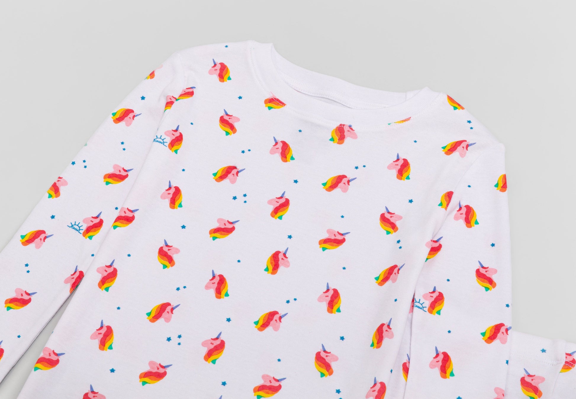 View of Pajama Set - Close up of unicorn print (with colorful unicorns, blue stars, and blue GMM logos). 
 Pajamas are white fabric with a vibrant unicorn print.  Pajamas are long-sleeved and made from GOTS certified, 100% organic cotton.
good morning monsters pajamas, loungewear, sleepwear, pajamas, boys, girls, baby, unisex