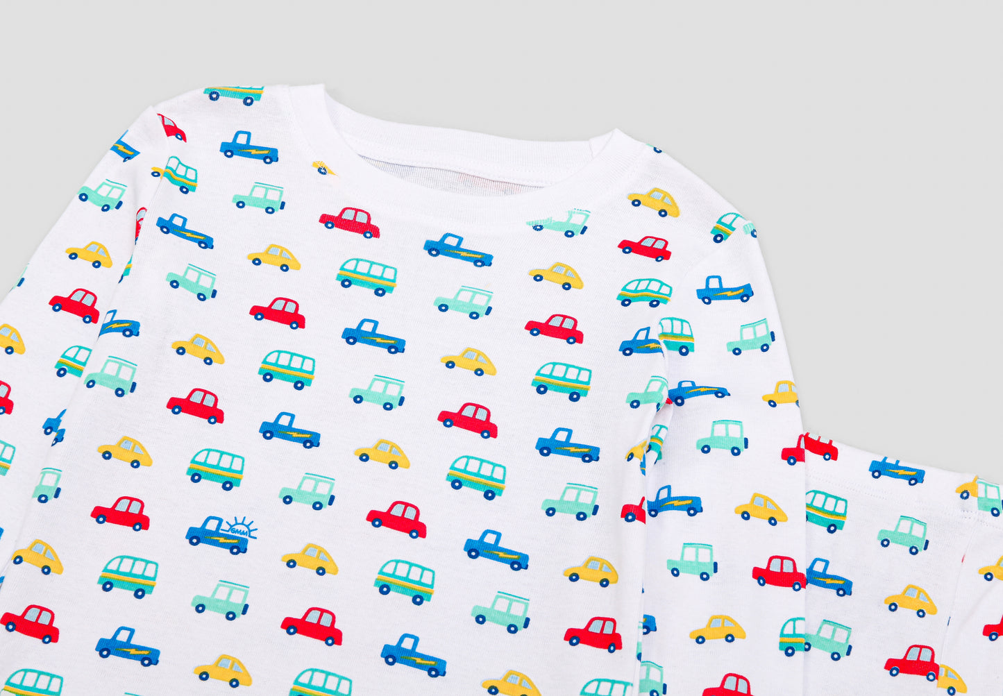 View of Pajama Set - Close up of vehicles print (with colorful cars,  buses, jeeps & vans,  and blue GMM logos). 
 Pajamas are white fabric with a vibrant vehicles print.  Pajamas are long-sleeved and made from 100% GOTS certified organic cotton.
good morning monsters pajamas, loungewear, sleepwear, pajamas, boys, girls, baby, unisex