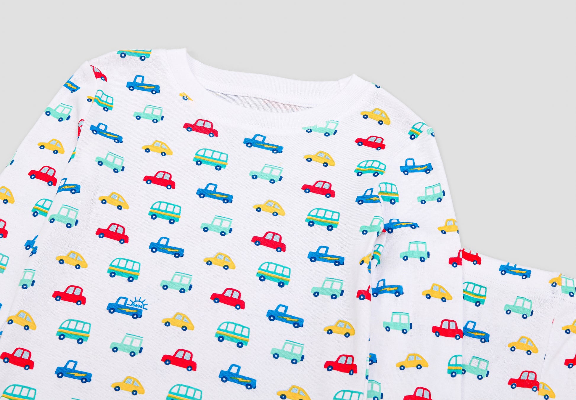 View of Pajama Set - Close up of vehicles print (with colorful cars,  buses, jeeps & vans,  and blue GMM logos). 
 Pajamas are white fabric with a vibrant vehicles print.  Pajamas are long-sleeved and made from 100% GOTS certified organic cotton.
good morning monsters pajamas, loungewear, sleepwear, pajamas, boys, girls, baby, unisex