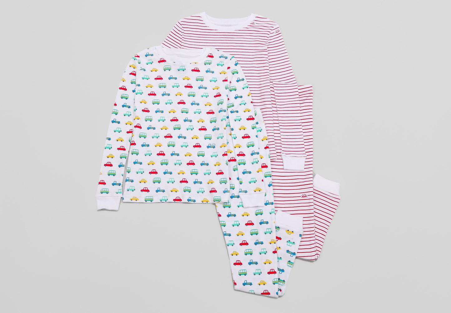 View of 2 PJ Sets side by side (Vehicles & Red Stripes) - Tops & Bottoms. Pajamas are white fabric with vibrant vehicles or bright red stripes, along with our fun GMM logo.  Pajamas are long-sleeved and made from 100% GOTS certified organic cotton.
good morning monsters pajamas, loungewear, sleepwear, pajamas, boys, girls, baby, unisex