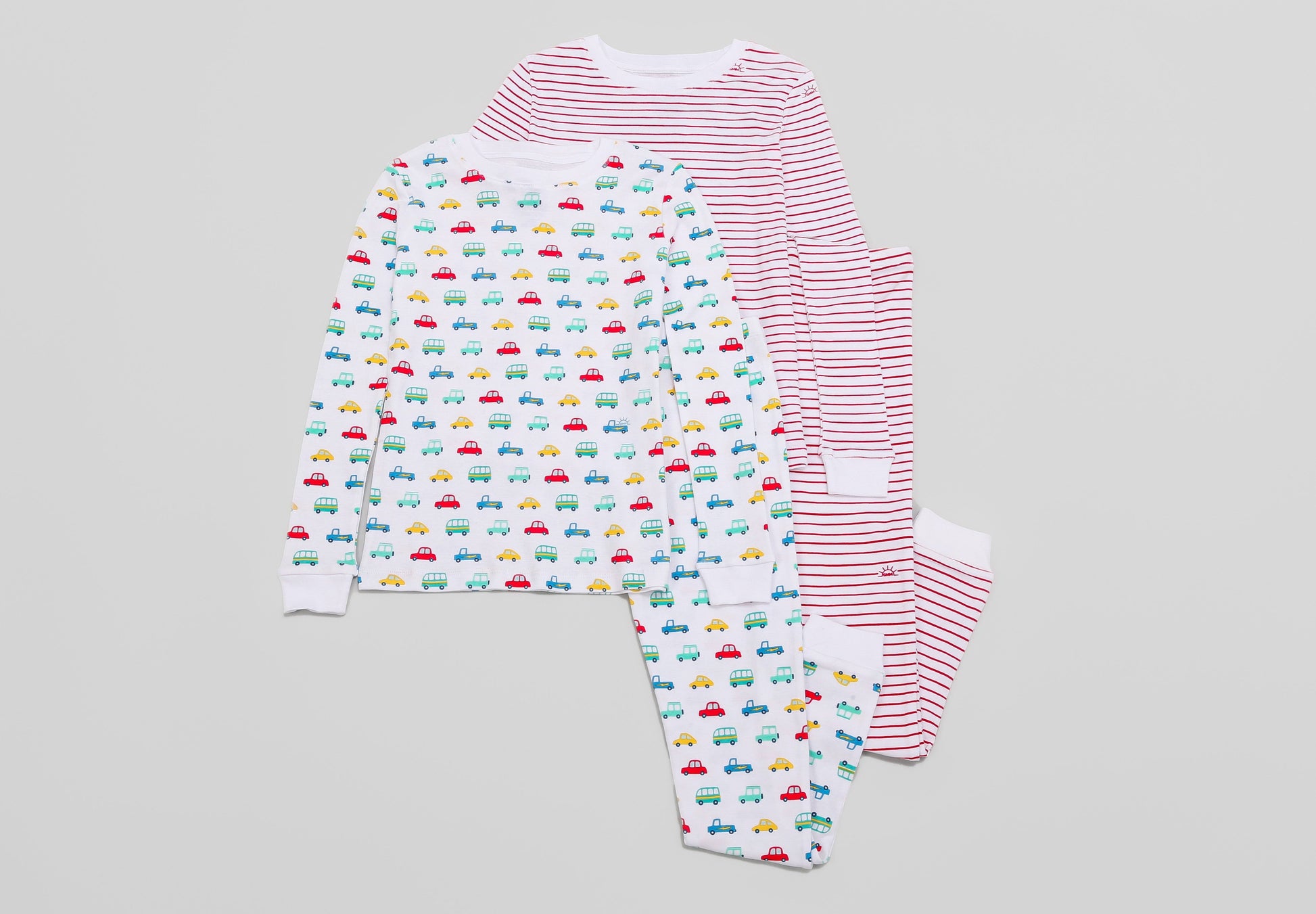 View of 2 PJ Sets side by side (Vehicles & Red Stripes) - Tops & Bottoms. Pajamas are white fabric with vibrant vehicles or bright red stripes, along with our fun GMM logo.  Pajamas are long-sleeved and made from 100% GOTS certified organic cotton.
good morning monsters pajamas, loungewear, sleepwear, pajamas, boys, girls, baby, unisex