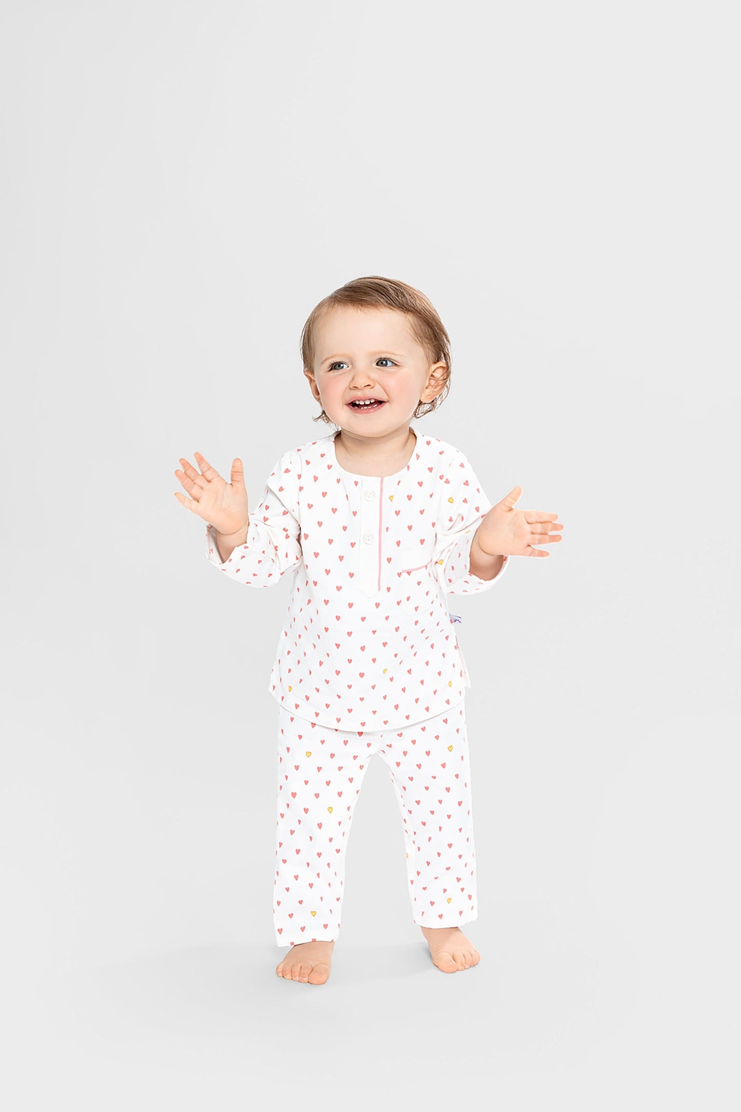 model wearing hearts print pajamas (solid white fabric with pink hearts); good morning monsters woven pajamas, loungewear, sleepwear, loose-fitting pajamas, boys, girls, baby, unisex