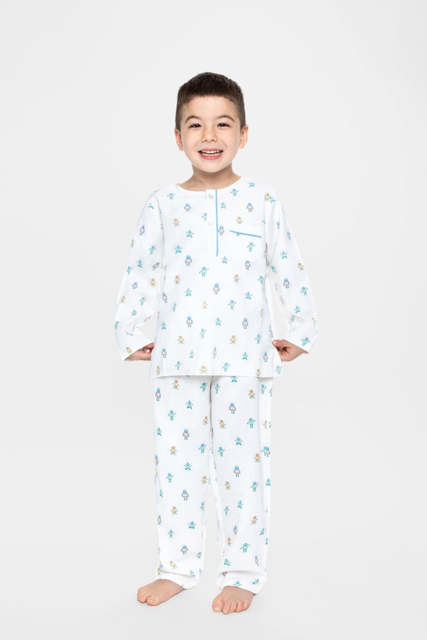 model wearing robots print pajamas (solid white fabric with colorful robots), good morning monsters woven pajamas, loungewear, sleepwear, loose-fitting pajamas, boys, girls, baby, unisex