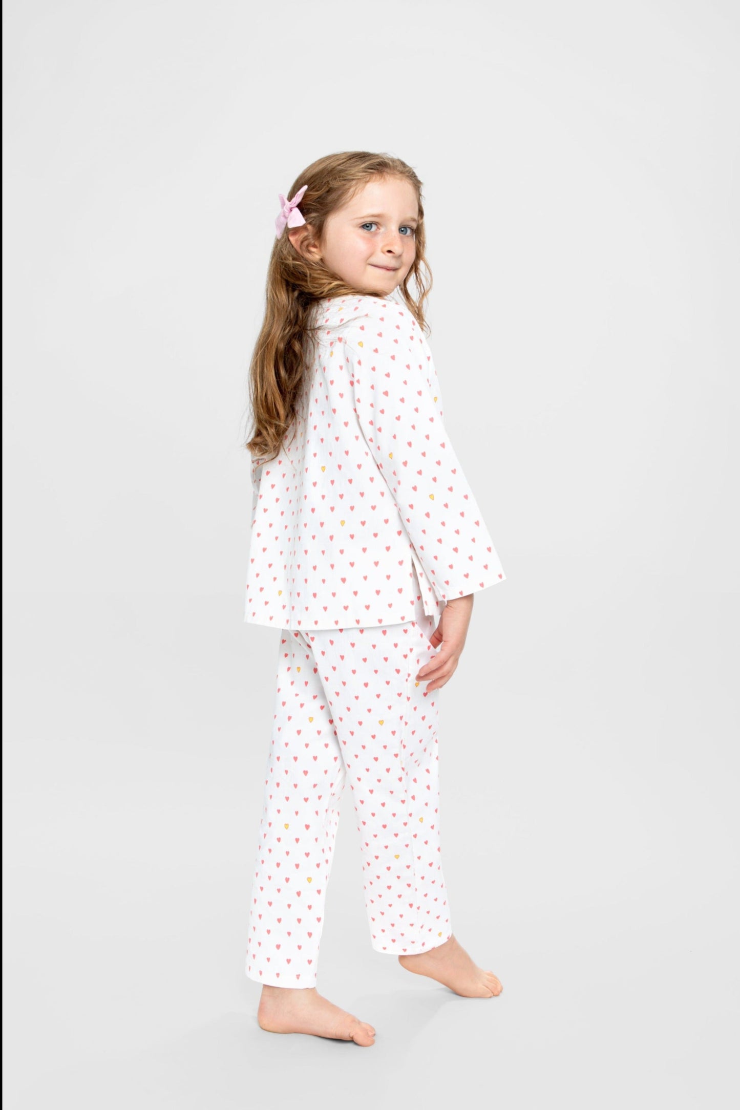 model wearing hearts print pajamas (solid white fabric with pink hearts); good morning monsters woven pajamas, loungewear, sleepwear, loose-fitting pajamas, boys, girls, baby, unisex