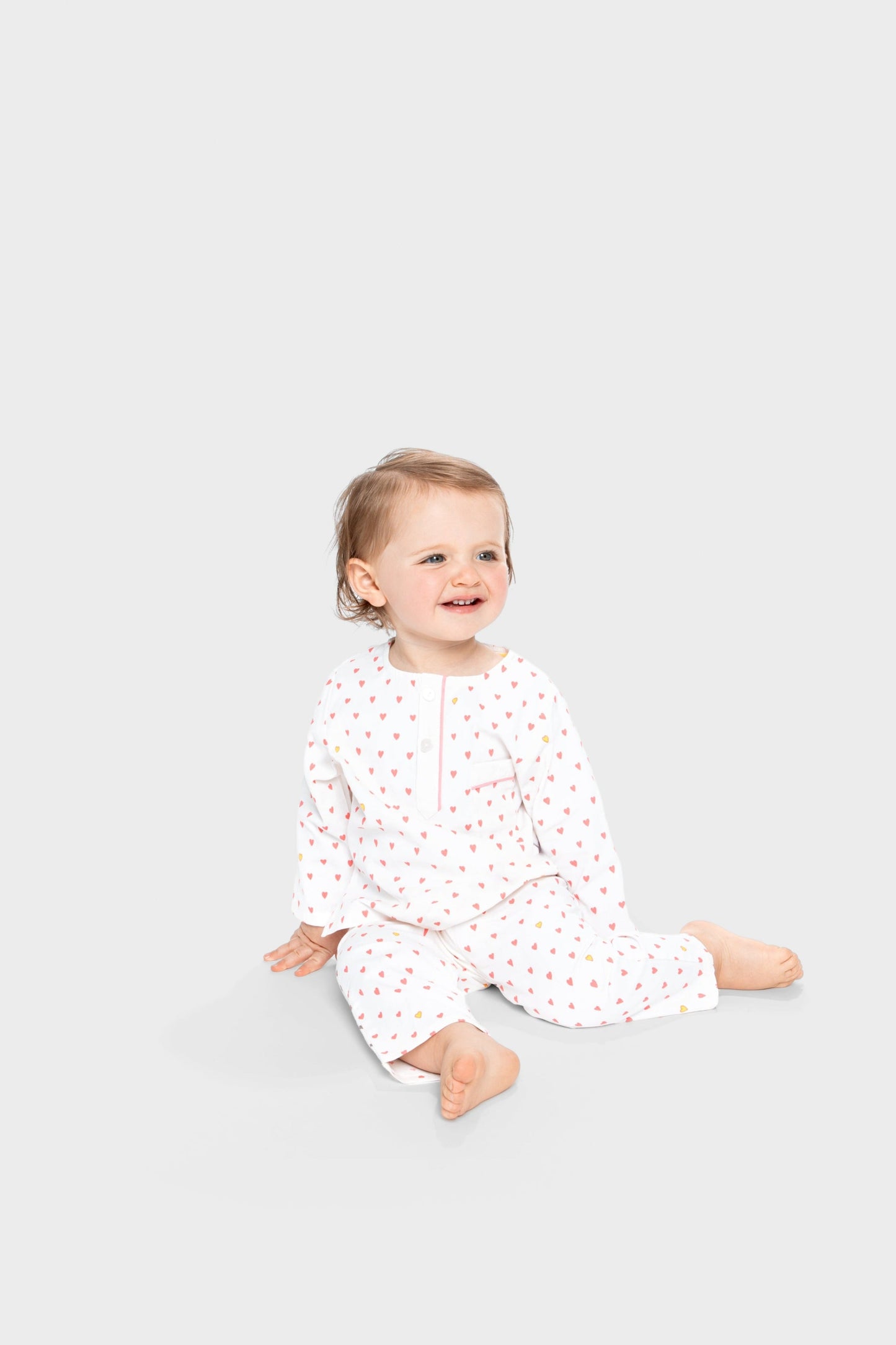 model wearing hearts print pajamas (solid white fabric with pink hearts); good morning monsters woven pajamas, loungewear, sleepwear, loose-fitting pajamas, boys, girls, baby, unisex