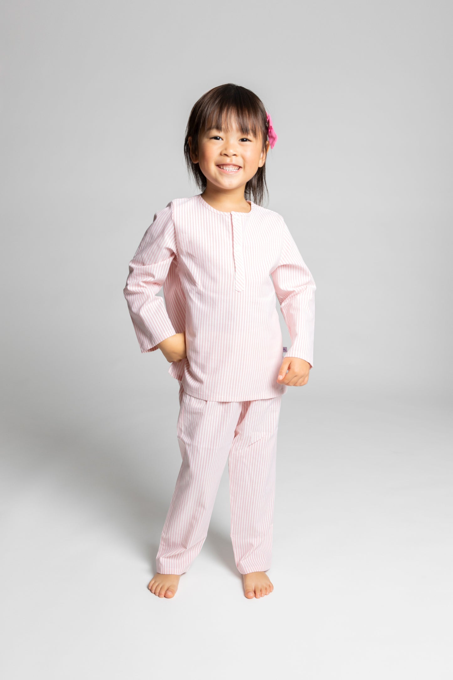 model wearing pink and white pinstripe pajamas, good morning monsters woven pajamas, loungewear, sleepwear, loose-fitting pajamas, boys, girls, baby, unisex