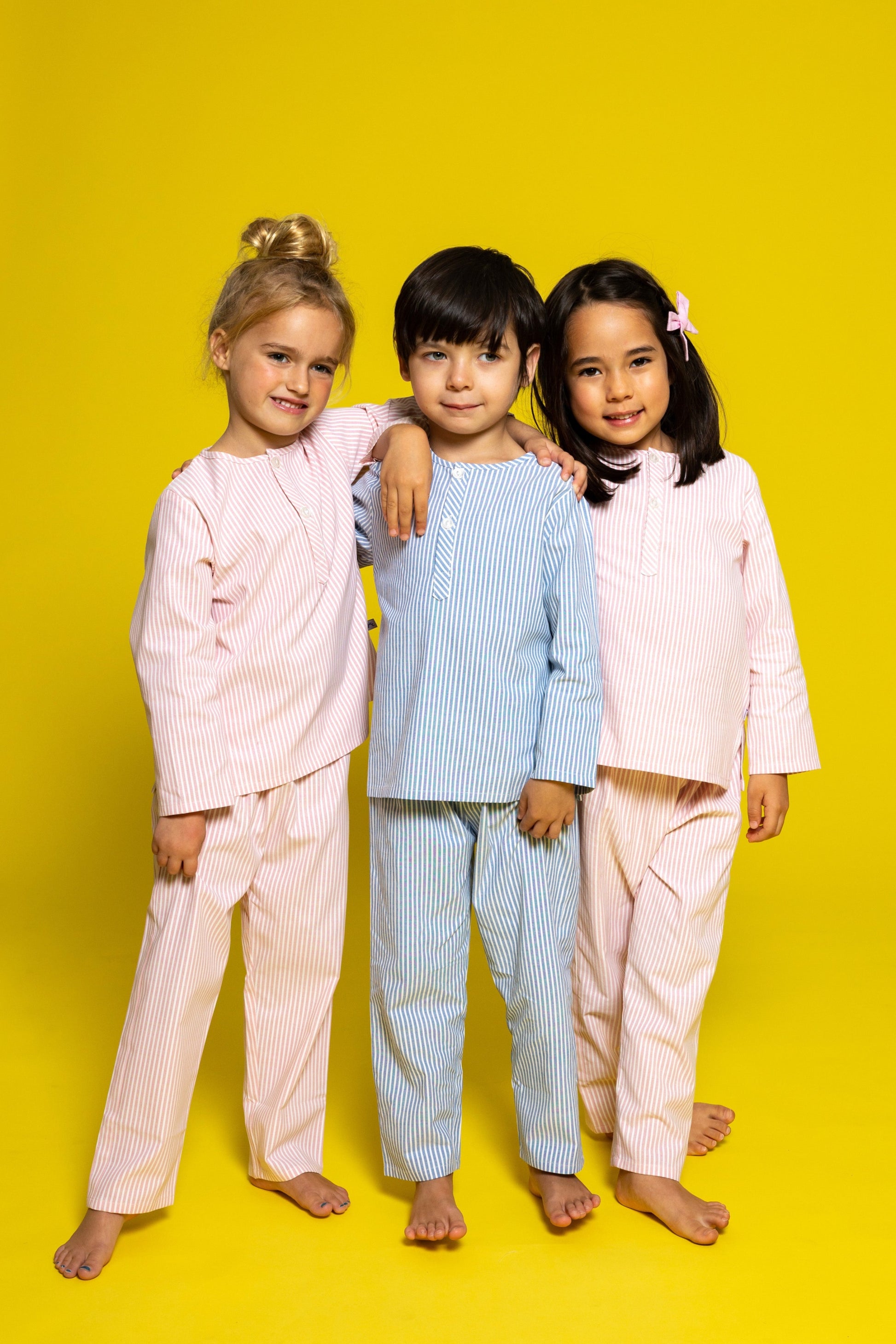 three models wearing good morning monsters pinstripe pajamas (two models are wearing pink pinstripes, the center model is wearing blue pinstripes), good morning monsters woven pajamas, loungewear, sleepwear, loose-fitting pajamas, boys, girls, baby, unisex