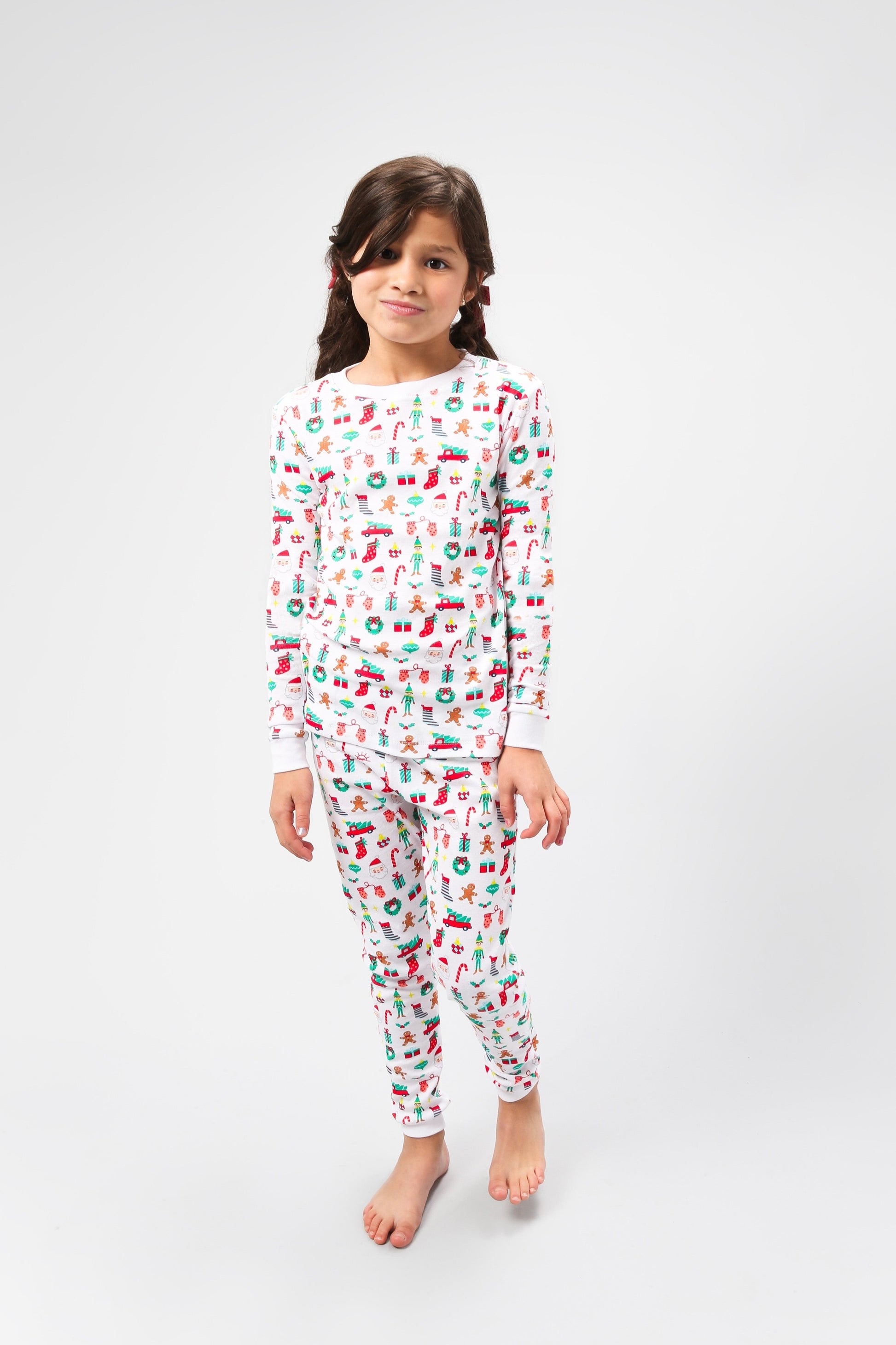 Front view of model wearing Christmas, festive, Santa, Elves, Classic Christmas, Holiday Ornaments, Stockings, Gingerbread, Red Trucks pajama set.  
Pajamas are white, lightweight fabric with a vibrant Christmas print.  Pajamas are long-sleeved and made from GOTS certified, 100% organic cotton.
good morning monsters pajamas, loungewear, sleepwear, pajamas, boys, girls, baby, unisex