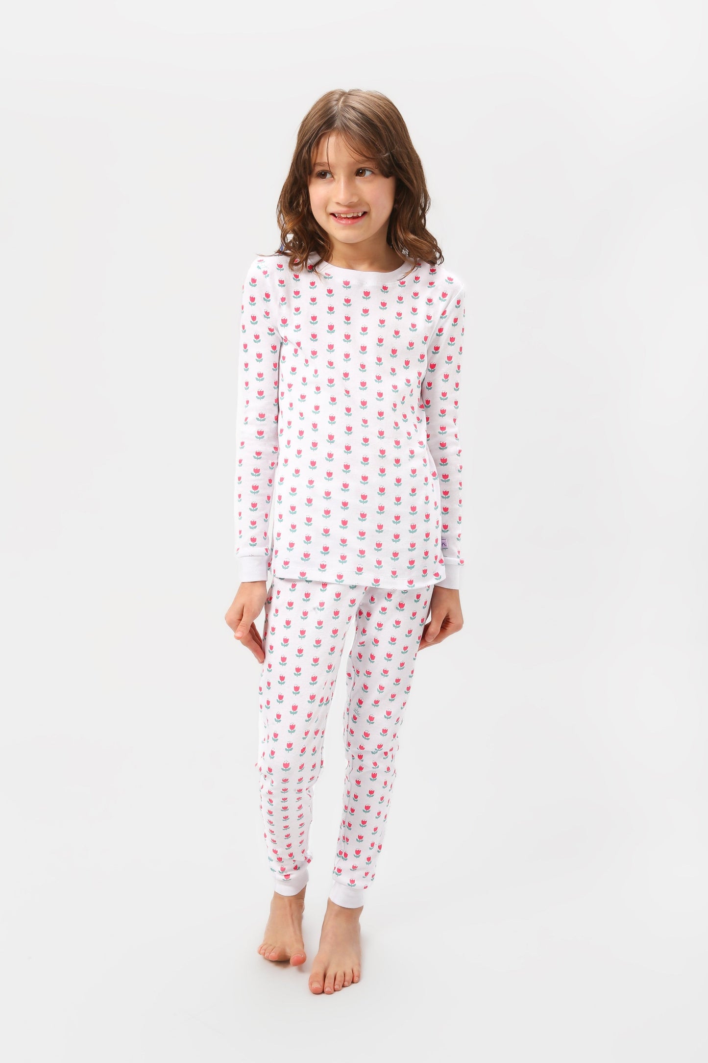 Front view of model wearing tulips pajama set.  
Pajamas are white, lightweight fabric with a vibrant tulips print (bright pink tulips with turquoise leaves).  Pajamas are long-sleeved and made from GOTS certified, 100% organic cotton.
good morning monsters pajamas, loungewear, sleepwear, pajamas, boys, girls, baby, unisex