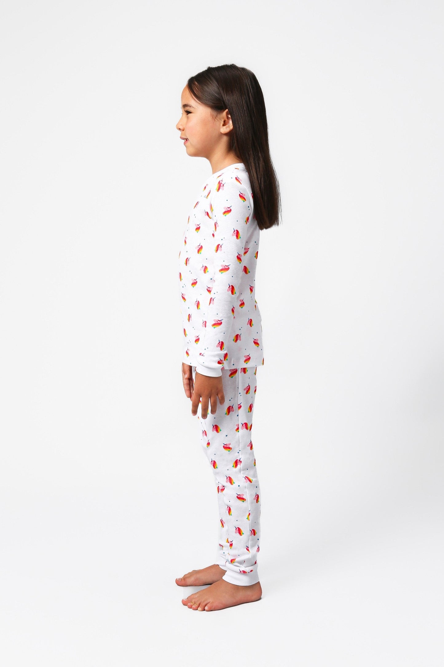 Side view of model wearing unicorn pajama set.  
Pajamas are white, lightweight fabric with a vibrant, colorful unicorn print.  Pajamas are long-sleeved and made from GOTS certified, 100% organic cotton.
good morning monsters pajamas, loungewear, sleepwear, pajamas, boys, girls, baby, unisex
