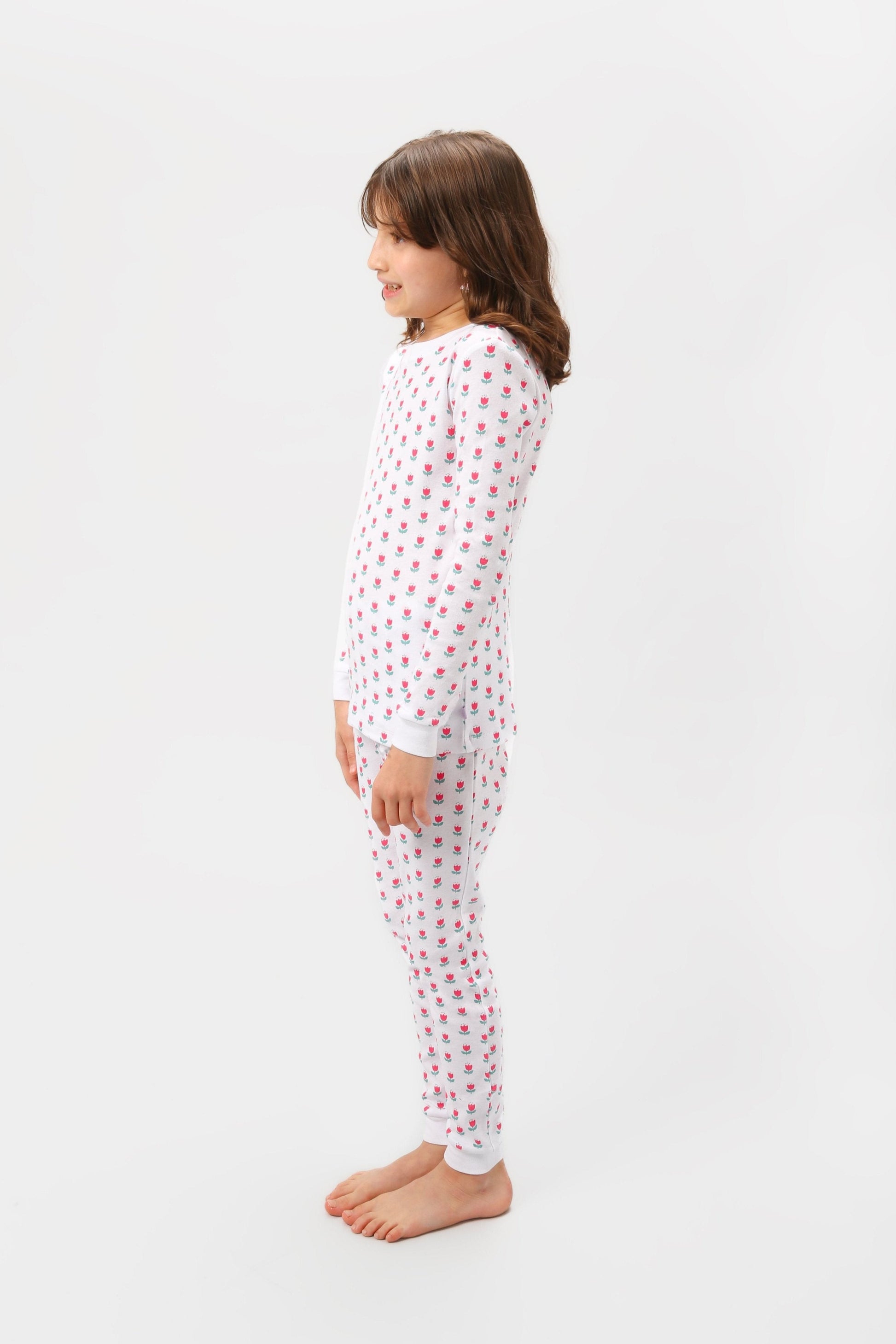 Side view of model wearing tulips pajama set.  
Pajamas are white, lightweight fabric with a vibrant tulips print (bright pink tulips with turquoise leaves).  Pajamas are long-sleeved and made from GOTS certified, 100% organic cotton.
good morning monsters pajamas, loungewear, sleepwear, pajamas, boys, girls, baby, unisex