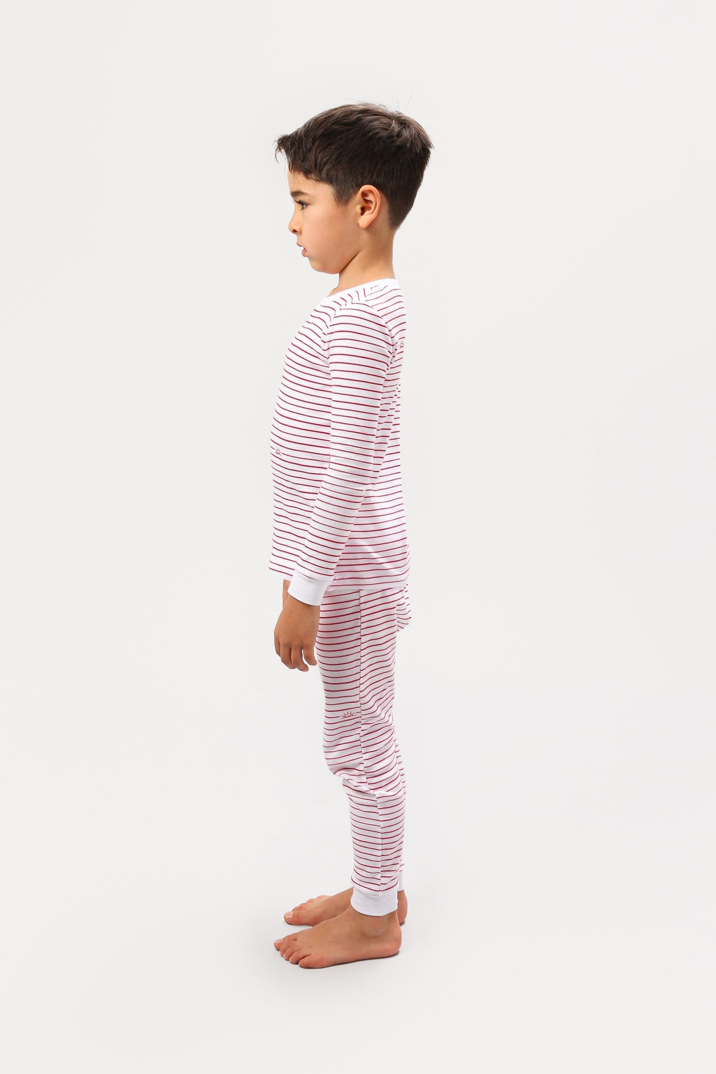 Side view of model wearing red stripes pajama set.  
Pajamas are white, lightweight  fabric with playful red stripes throughout (along with our GMM logo sprinkled in).  Pajamas are long-sleeved and made from GOTS certified, 100% organic cotton.
good morning monsters pajamas, loungewear, sleepwear, pajamas, boys, girls, baby, unisex