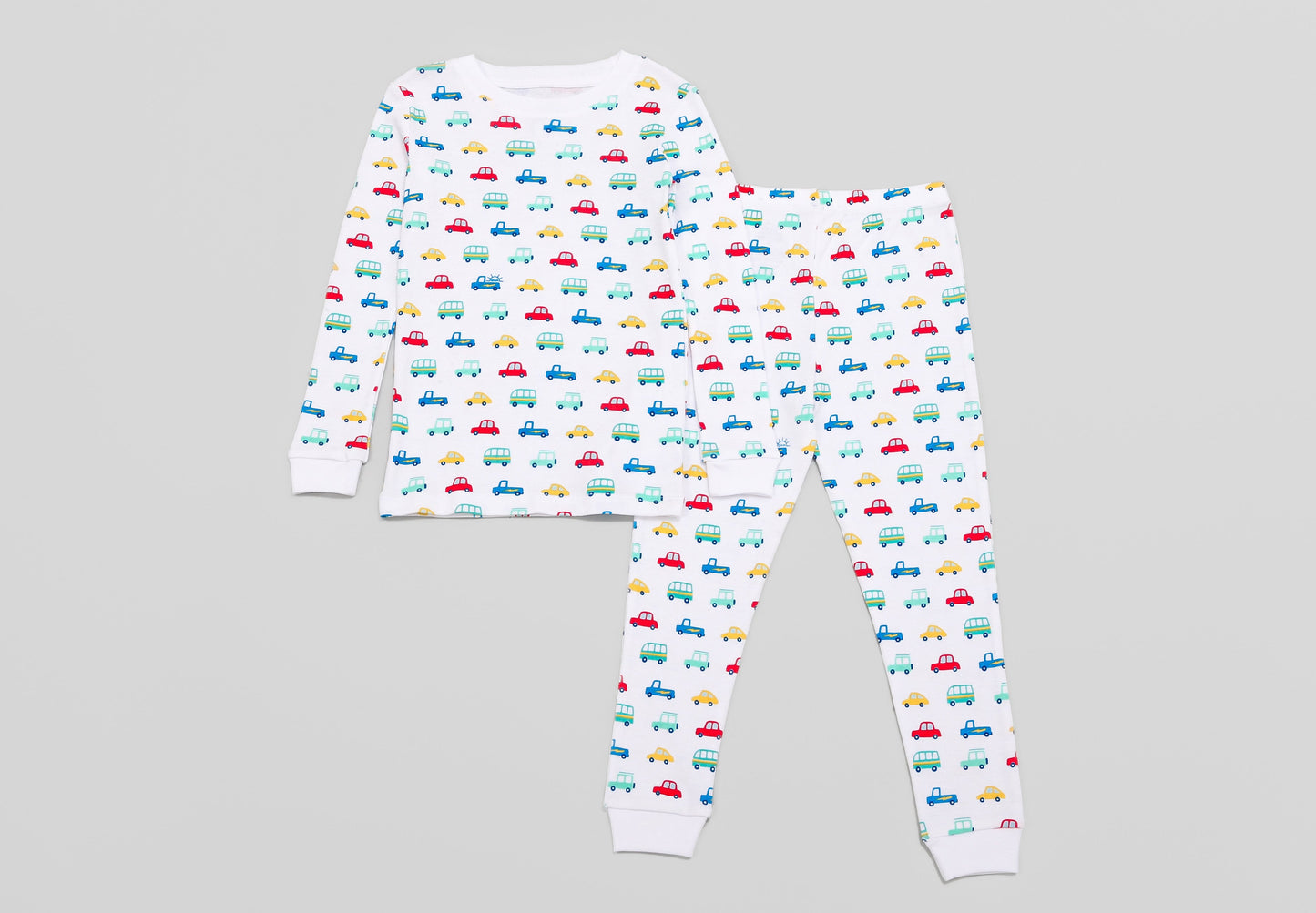 View of Pajama Set - Top & Bottom. 
 Pajamas are white fabric with a vibrant, colorful vehicles print with cars, jeeps, trucks, and buses.  Pajamas are long-sleeved and made from 100% GOTS certified organic cotton.