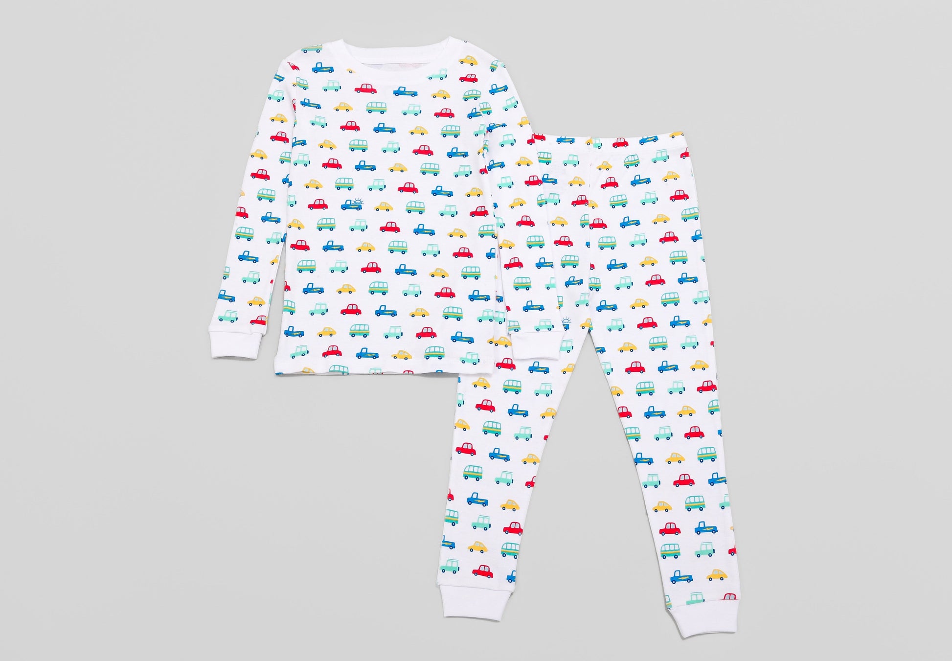 View of Pajama Set - Top & Bottom. 
 Pajamas are white fabric with a vibrant, colorful vehicles print with cars, jeeps, trucks, and buses.  Pajamas are long-sleeved and made from 100% GOTS certified organic cotton.