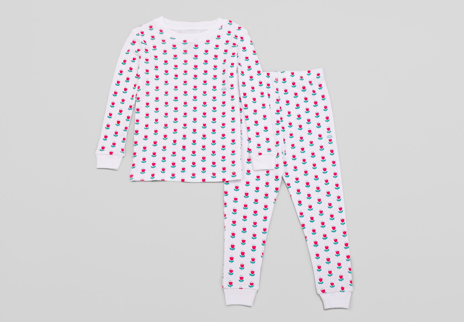 View of Pajama Set - Top & Bottom. 
 Pajamas are white fabric with a vibrant, tulips print (bright pink tulips with turquoise leaves).  Pajamas are long-sleeved and made from GOTS certified, 100% organic cotton.