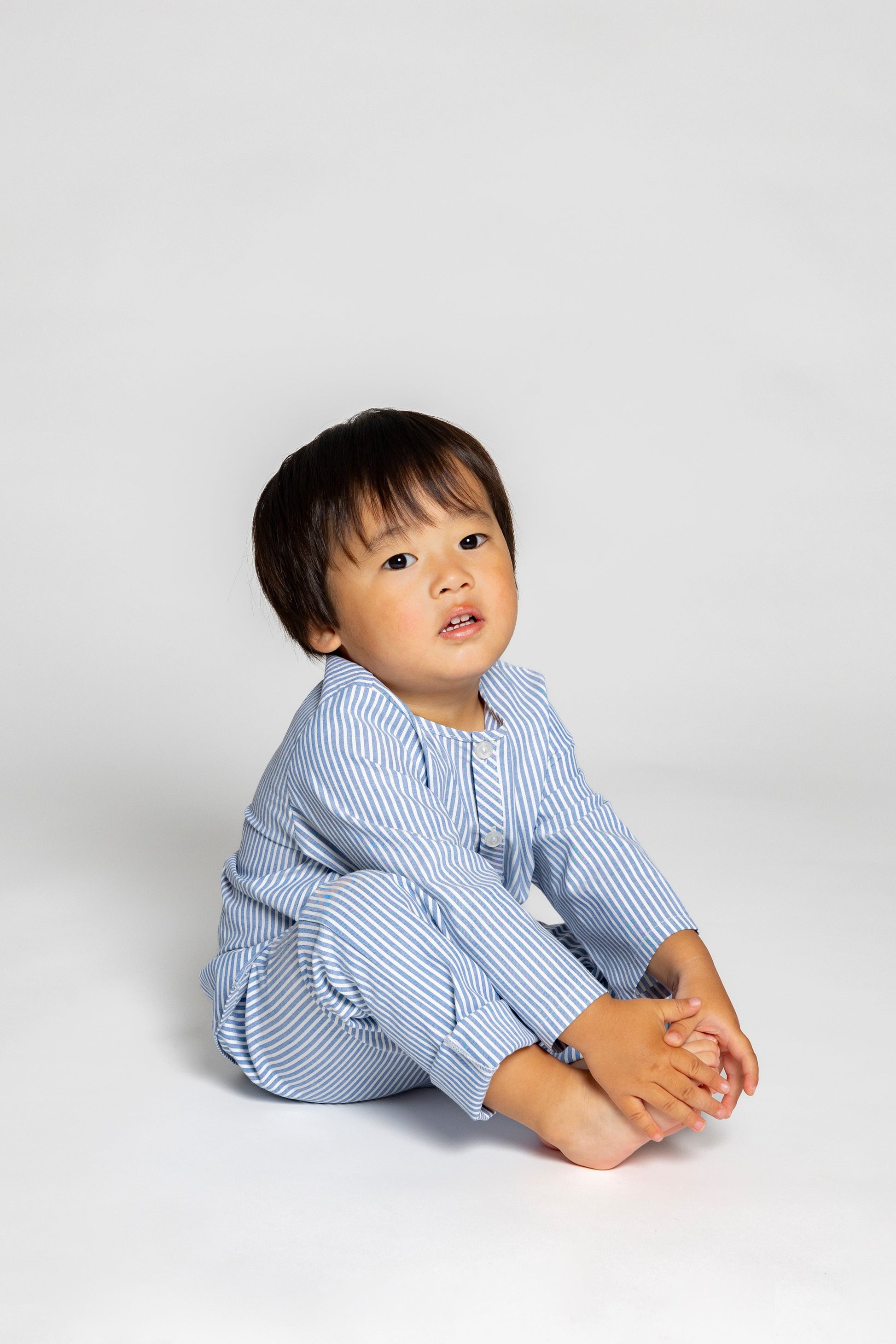 model wearing blue and white pinstripe pajamas, good morning monsters woven pajamas, loungewear, sleepwear, loose-fitting pajamas, boys, girls, baby, unisex